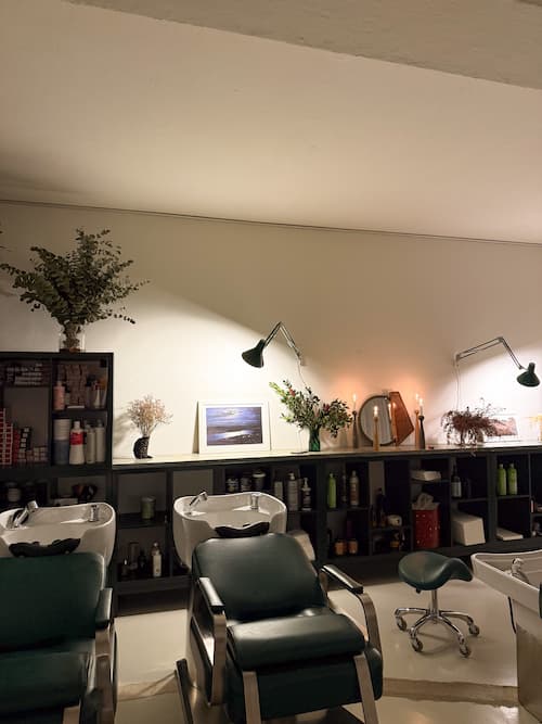 Hair-washing area with green chairs and basins at Brama Hair Studio