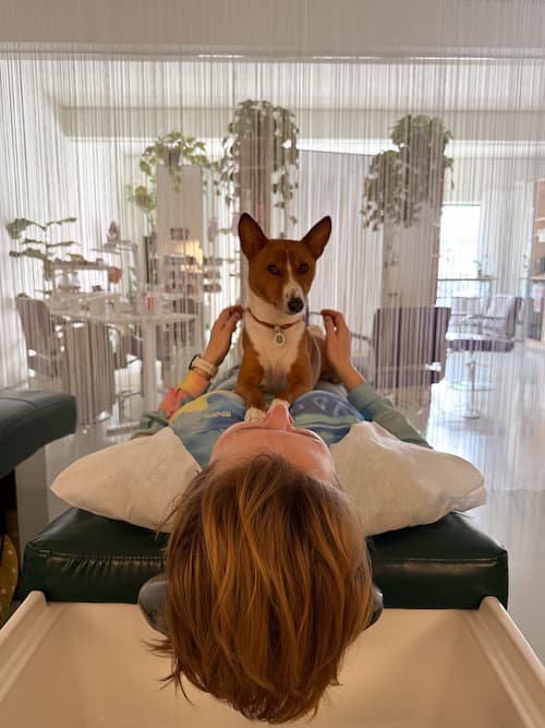 Dog sitting with a client at a hair-washing basin in Brama Hair Studio