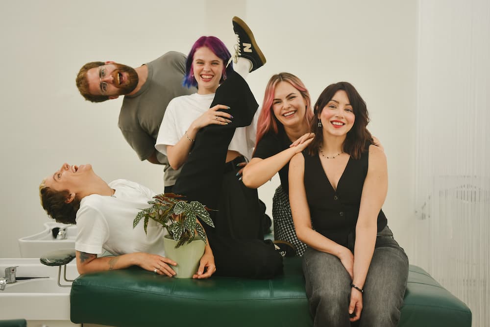 Five Brama Hair Studio team members posing and laughing together